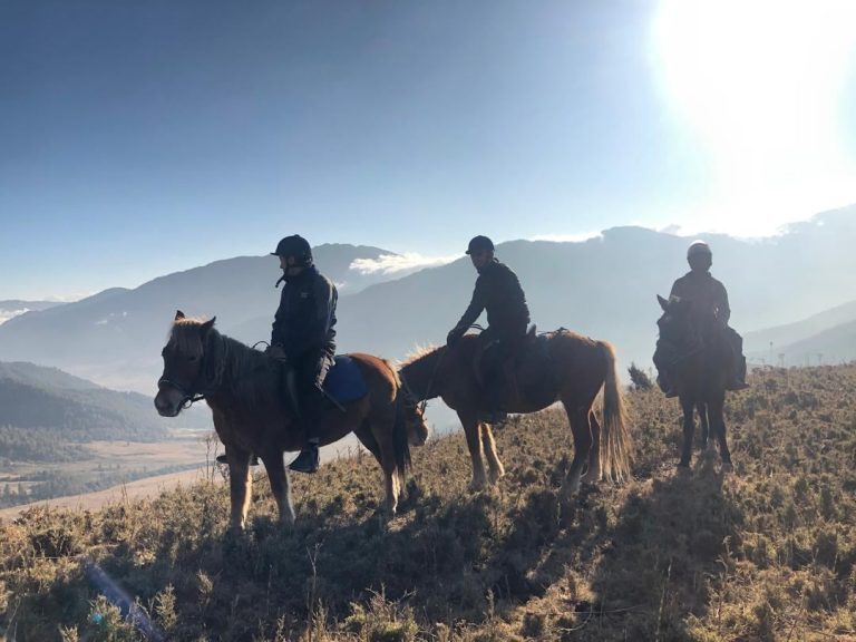 Three riders on a ridge at sunrise above the Phobjikha Valley